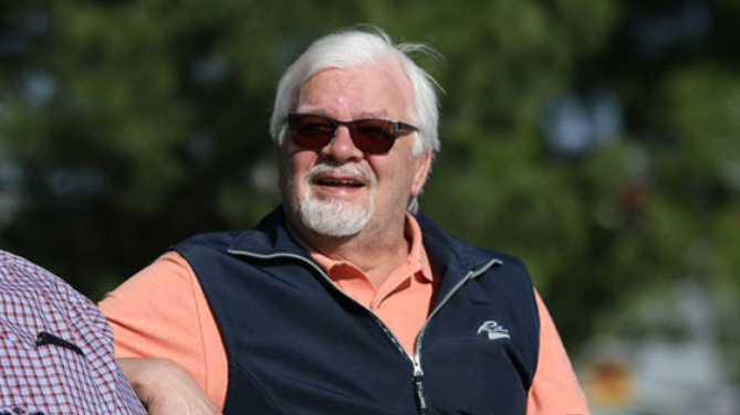 Kuvituskuvassa harmaapartainen ja -hiuksinen mies puolilähikuvassa, hymyilee, aurinko paistaa ja hänellä on aurinkolasit päässän.