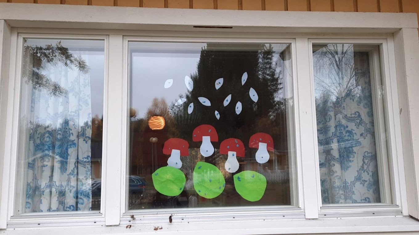 Ulkoa kuvattu kolmeosainen ikkuna, jossa lasten tekemiä koristeluja.