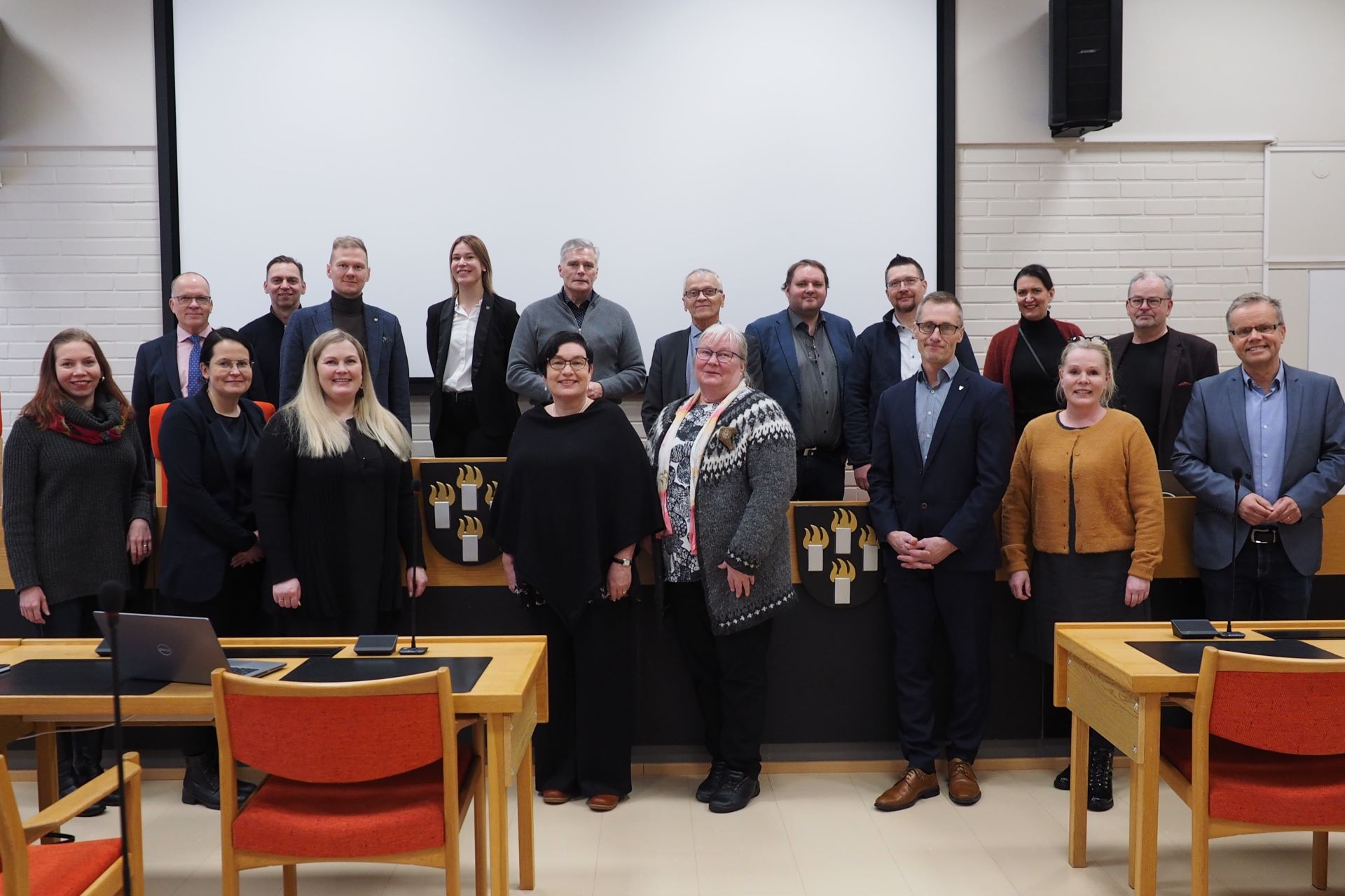 18 henkilöä seisoo ryhmäkuvassa.