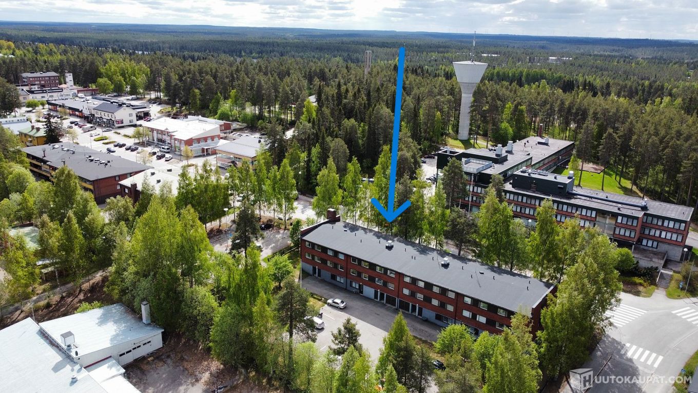 kesällä otettu ilmakuva Suomussalmen keskustasta, sinistellä nuolella on merkitty kunnantaloa vastapäätä sijaitseva kerrostalo.